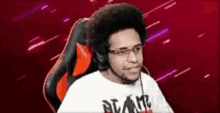 a man wearing headphones and glasses is sitting in a chair with a red background .