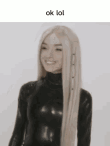 a woman with long blonde hair is wearing a black bodysuit and smiling .