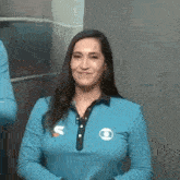 a woman wearing a blue shirt is smiling and looking at the camera .