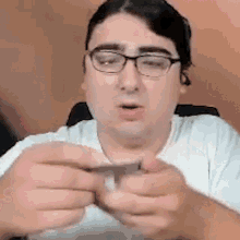 a man wearing glasses is holding something in his hands .