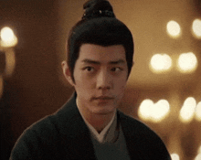 a man with a bun on his head is wearing a black jacket .