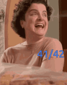 a woman with curly hair is laughing with the number 41/42 written on her chest