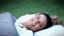 a woman is smiling while laying on a pillow in the grass .