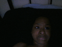 a woman laying on a bed with a black blanket on top of her head