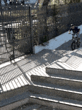 a man riding a bike down a set of stairs in front of a fence