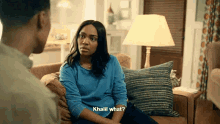 a woman in a blue sweater is sitting on a couch talking to a man and asking khalil what .