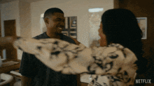 a man and a woman are hugging each other with a netflix logo in the background