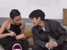 two men are sitting on a couch and one of them has a name tag that says esss