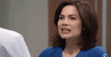 a woman in a blue scrub is talking to a man in a white shirt .