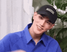 a young man wearing a blue shirt and a black baseball cap is smiling .