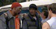 a man wearing a red beanie and a black hat talks to two other men