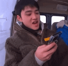 a young man is sitting in a car looking at his cell phone