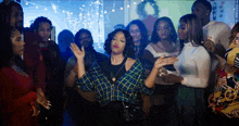 a woman in a plaid shirt is dancing in front of a crowd