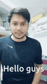 a man in a black nike shirt is standing in front of a shelf with pillows and says hello guys