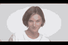 a woman with short brown hair is wearing a white t-shirt