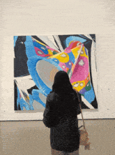 a woman looks at a colorful painting on the wall