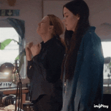 two women are standing next to each other in a room with the words imgplay below them