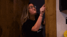 a woman wearing glasses is standing in a doorway and making a funny face .