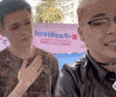 two men are standing in front of a pink sign that says invites9-x