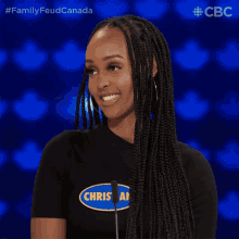 a woman wearing a black shirt that says chris on it stands in front of a microphone