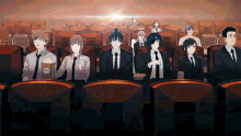 a group of people are sitting in a theater watching a movie and eating popcorn