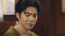 a young man in a green shirt is smiling and giving a peace sign