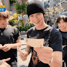 a man wearing a black beanie holds a piece of paper in his hand