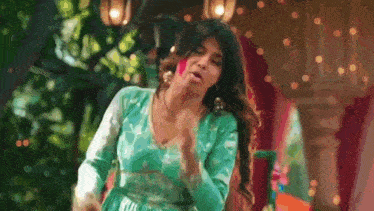 a woman in a green dress is dancing in front of a lantern .