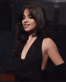 a woman in a black dress is standing in a dark room .