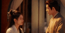 a man and a woman are standing next to each other and looking at each other in a room .