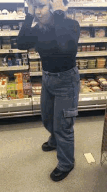 a woman is standing in a grocery store talking on a cell phone .