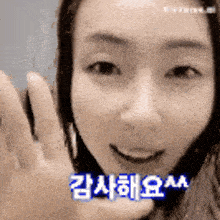 a woman is smiling and waving her hand in a black and white photo with korean writing on it .