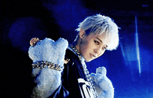 a young man with white hair is wearing a black shirt with the letter n on it