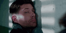 a man leans against a wall with his head resting on it
