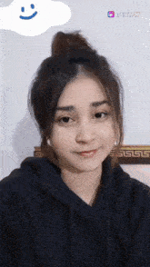 a woman wearing a black hoodie is smiling with a beat.ly sticker in the background