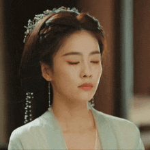 a woman with her eyes closed wearing earrings and a headband