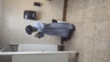 a man is standing in a public restroom with a paper towel dispenser on the wall .