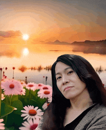 a woman stands in front of a field of pink daisies with a sunset in the background
