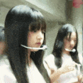 a girl wearing a headset is standing next to another girl with long hair .