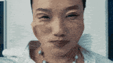 a close up of a woman 's face with a pearl necklace around her neck