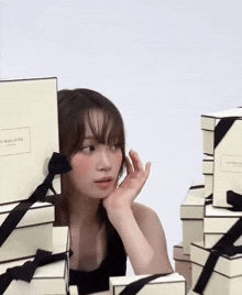 a woman is standing in front of a stack of jo malone boxes .