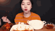 a woman is eating food with chopsticks at a table