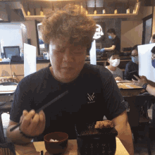 a man wearing a ny shirt is eating food