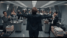 a man in a suit stands in front of a group of people in an office