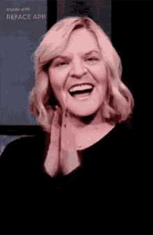 a woman is smiling and clapping her hands in front of a screen .
