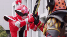 a red superhero is holding a sword while another superhero is holding a sword