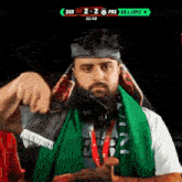 a man wearing headphones and a scarf around his neck is giving a thumbs up sign .