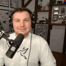 a man wearing headphones stands in front of a microphone with a hummingbird on his shirt