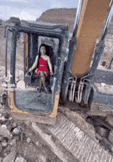 a woman in a red dress is driving a large excavator