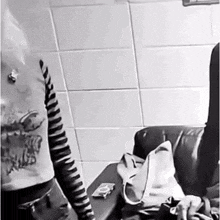 a black and white photo of a person sitting on a chair in a bathroom .